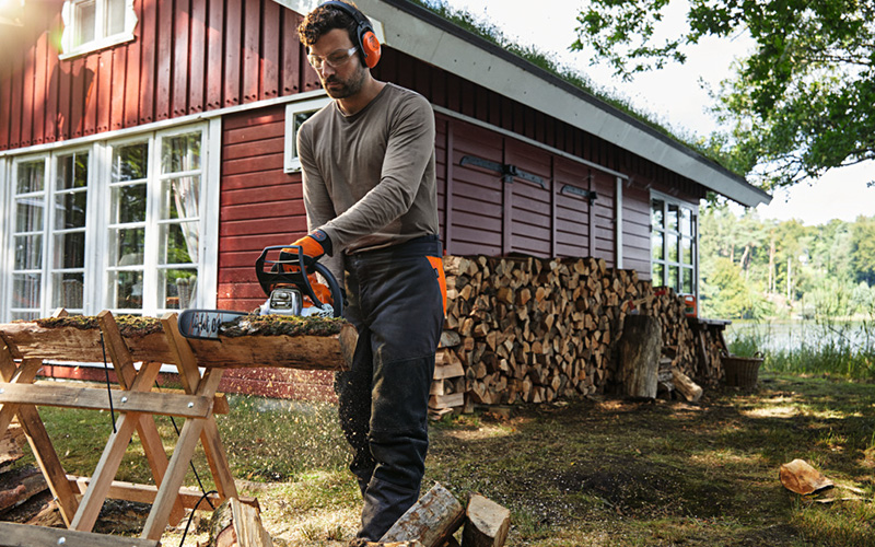 Man wearing STIHL protective gear cutting wood with a STIHL chainsaw