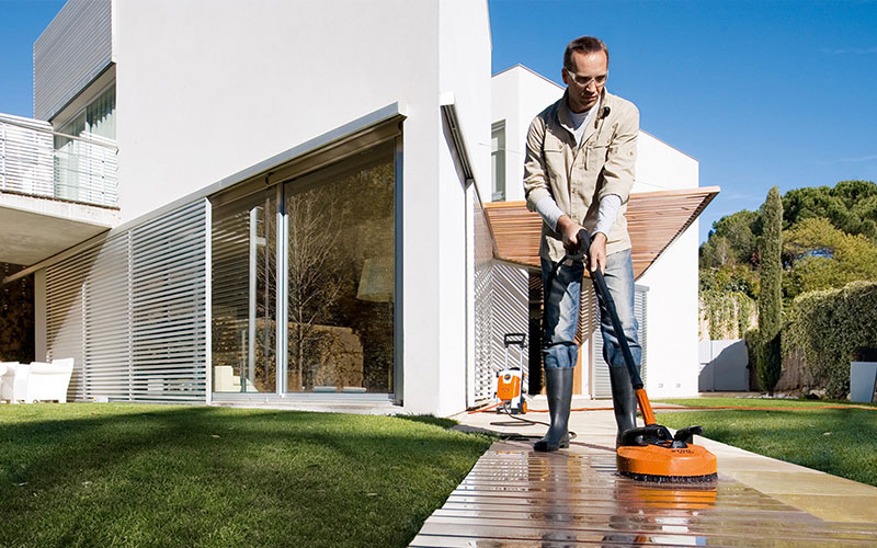 A man using an Electric Water Blaster with a Patio Cleaner to clean his deck