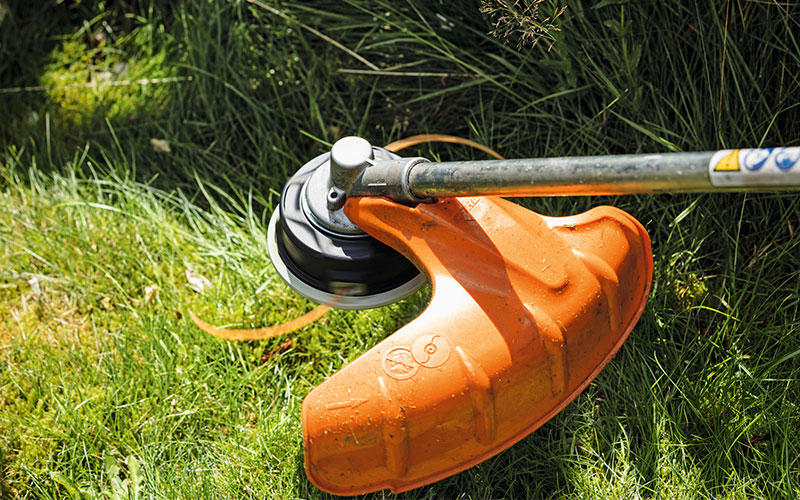 Close up of a line trimmer mowing head cutting grass