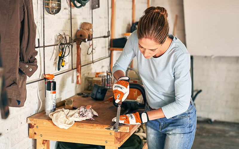 A woman sharpening the teeth of her Hedge Trimmer with a flat file